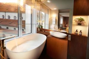 a bathroom with a large white tub and a sink at BEYOND by Geisel in Munich +37 photos