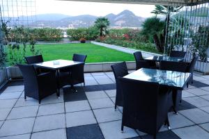 un patio avec des tables et des chaises ainsi qu'un jardin dans l'établissement Tower Genova Airport - Hotel & Conference Center, à Gênes