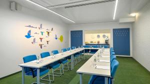 a conference room with white tables and blue chairs at Hotel Metropol in Warsaw