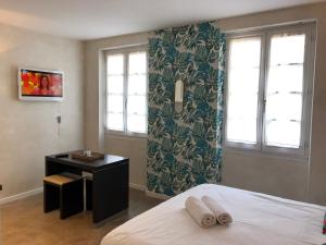 a bedroom with a bed and a desk and windows at ALBI HOME - Vigan in Albi