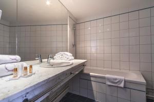 Baño blanco con lavabo y bañera en Hotel Ours Blanc - Victor Hugo, en Toulouse 30 fotos más