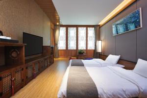 旌善Jeongseon Intoraon Hotel的一间卧室，配有两张床和一台平板电视