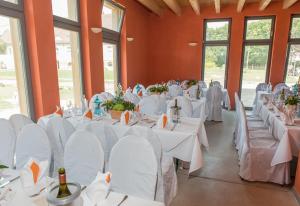 een kamer vol tafels en stoelen met witte tafelkleden bij Gästehaus am Landgut in Schönwalde