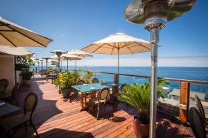 a deck with tables and chairs and umbrellas at La Casa Del Camino in Laguna Beach