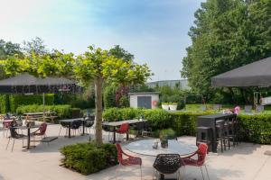 a patio with tables and chairs and a grill at Novotel Rotterdam - Schiedam in Schiedam