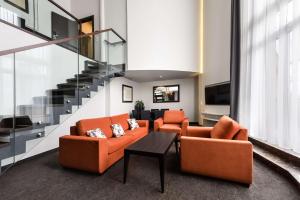 a living room with orange chairs and a staircase at Radisson Blu Sobieski in Warsaw