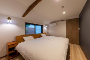 a bedroom with a large white bed and a window at 風早邸海音 kazahayatei mion in Hōjō