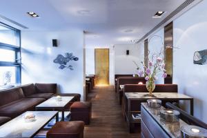 a restaurant with couches and tables and flowers at The Mandala Berlin, a Member of Design Hotels in Berlin