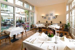 a restaurant with white tables and chairs and windows at martas Hotel Albrechtshof Berlin in Berlin