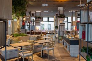a restaurant with tables and chairs and a couch at IntercityHotel Berlin Airport BER Terminal 1 & 2 in Schönefeld
