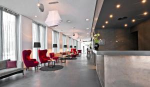 a waiting room with red chairs and a bar at COSMO Hotel Berlin Mitte in Berlin