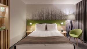 um quarto de hotel com uma cama e uma cadeira verde em Holiday Inn Frankfurt - Alte Oper by IHG em Frankfurt am Main