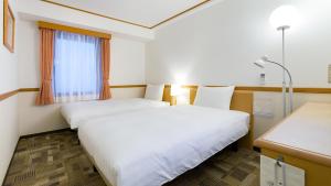 a hotel room with two beds and a window at Toyoko Inn Fukuyama-eki Shinkansen Minami-guchi in Fukuyama