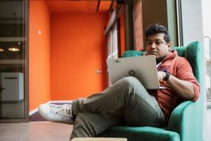 a man sitting in a chair with a laptop at easyHotel Paris Nord Aubervilliers in Aubervilliers +36 photos