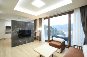 een woonkamer met een televisie, een bank en een tafel bij Pyeongchang The White Hotel in Pyeongchang 