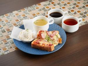 een blauw bord met een broodje en twee kopjes koffie bij Grand Cabin Hotel Naha Oroku in Naha +37 foto's