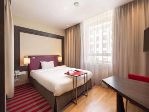 a hotel room with a bed and a table at Mercure Warszawa Grand in Warsaw
