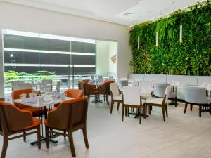 ein Restaurant mit Tischen und Stühlen und einer grünen Wand in der Unterkunft Hilton Garden Inn Santa Ana, San Jose in San José