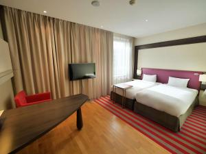 a hotel room with a large bed and a red chair at Mercure Warszawa Grand in Warsaw +37 photos