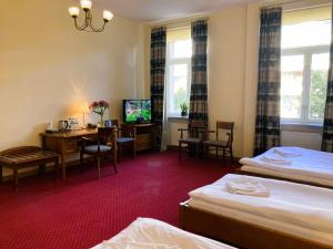 a hotel room with two beds and a desk and a television at Hotel Łazienkowski in Warsaw