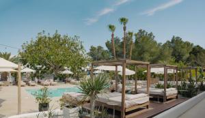 a resort with a pool with beds and umbrellas at Hotel Boutique & Spa Las Mimosas Ibiza in San Antonio Bay