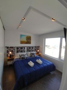 a bedroom with a blue bed with a large window at Rincon del Beagle in Ushuaia