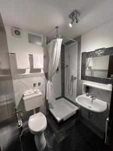 Un baño con inodoro, lavabo y ducha. en Runas Hotel, en Hallbergmoos