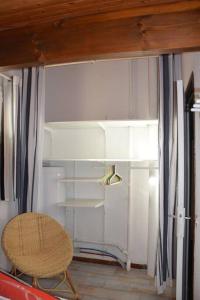 Cette chambre comprend une chaise et un réfrigérateur blanc. dans l'établissement Les maisons de L'Océan, aux Mathes