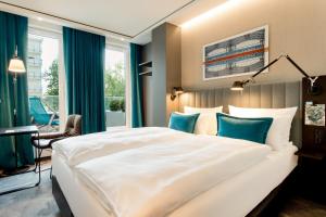 a bedroom with a large white bed with blue pillows at Motel One Berlin-Hauptbahnhof in Berlin