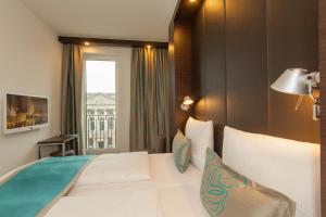una camera da letto con un grande letto bianco e una finestra di Motel One Berlin-Potsdamer Platz a Berlino