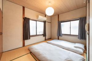 two beds in a room with two windows at Osaka Kanzakigawa Royal駅徒步1分 "private house 3 bed rooms "一棟貸し宿 in Osaka