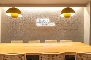 a large wooden table with chairs and a sign on a wall at Dash Living Gojo in Kyoto