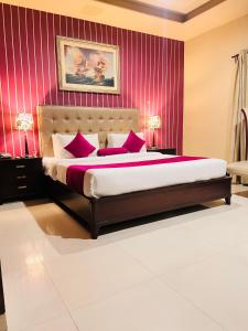 a bedroom with a large bed with red walls at Grand Regent Hotel and Suites in Faisalabad