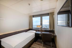 a hotel room with a bed and a desk and window at Park Inn by Radisson Berlin Alexanderplatz in Berlin