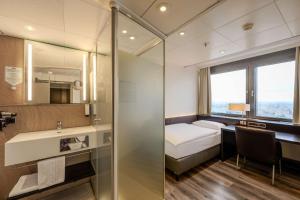 a bathroom with a bed and a sink and a mirror at Park Inn by Radisson Berlin Alexanderplatz in Berlin +37 photos