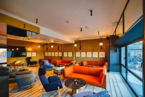 a living room with orange couches and blue chairs at Hotel MDM City Centre in Warsaw