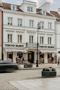 a car driving past a large white building at Colette - LoftAffair Collection in Warsaw