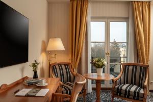 a hotel room with a desk and a table and chairs at Hotel Am Jägertor in Potsdam