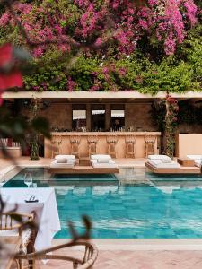 a swimming pool with tables and chairs and pink flowers at The Margi in Athens