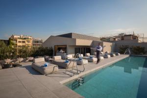 a hotel with a pool with chairs and a man standing next to it at Ohla Eixample in Barcelona