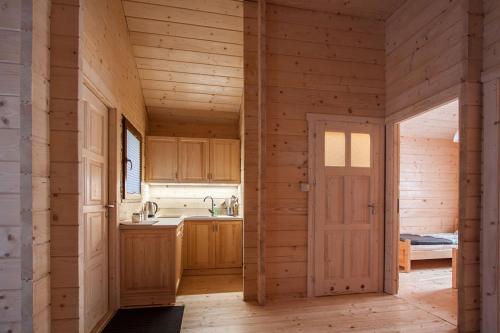 a kitchen with wooden walls and a door in a room at Domki Drewniane Przystań Kajaczek in Białobrzegi