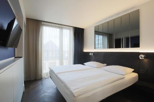 a bedroom with a large bed and a mirror at Hotel AMANO Grand Central in Berlin