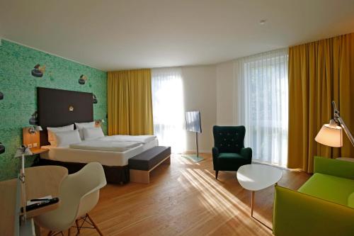 a hotel room with a bed and a chair at Grimm´s Berlin Potsdam in Teltow