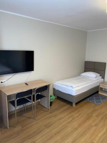 a bedroom with a bed and a desk with a flat screen tv at GRACJA in Warszawa