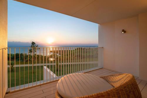 a balcony with a wicker chair and a view of the ocean at IRAPH SUI, a Luxury Collection Hotel, Miyako Okinawa in Miyako-jima