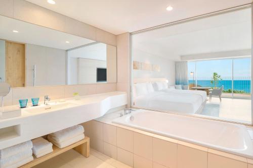 a bathroom with a tub and a bedroom with a bed at IRAPH SUI, a Luxury Collection Hotel, Miyako Okinawa in Miyako-jima