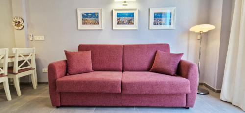 um sofá rosa com duas almofadas numa sala de estar em Malaga Lodge Apartments em Málaga