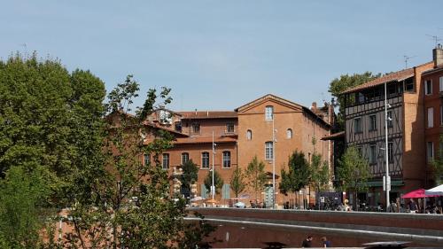 a group of buildings next to a river at Hôtel Restaurant d'Occitanie in Toulouse