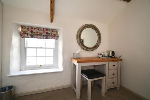 a bathroom with a table and a mirror and a window at Carew Inn in Tenby