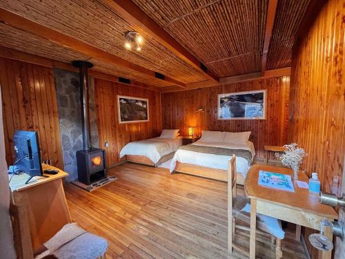 a bedroom with two beds and a tv in it at Hotel Último Paraíso in Cochrane
